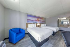 a room with two beds and a blue chair at Days Inn by Wyndham Fredericksburg North in Fredericksburg