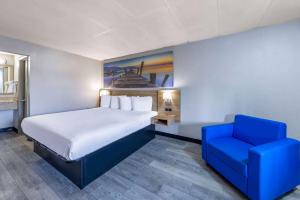 a bedroom with a bed and a blue chair at Days Inn by Wyndham Fredericksburg North in Fredericksburg