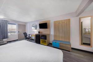 a hotel room with a bed and a desk and a table at Days Inn by Wyndham Fredericksburg North in Fredericksburg