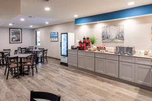 a restaurant with a counter and tables and chairs at Baymont by Wyndham Biloxi - Ocean Springs in Biloxi