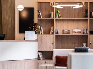 - un salon avec une télévision et des étagères avec des livres dans l'établissement Mercure Grenoble Centre Alpotel, à Grenoble