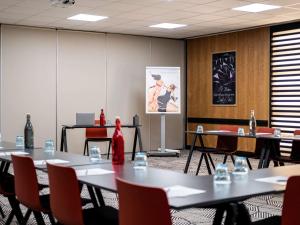 une salle de conférence avec des tables, des chaises et un tableau dans l'établissement Mercure Grenoble Centre Alpotel, à Grenoble