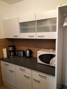 a kitchen with white cabinets and a microwave at Vier Jahreszeiten, Appartment 723, Hahnenklee - Bockswiese in Goslar