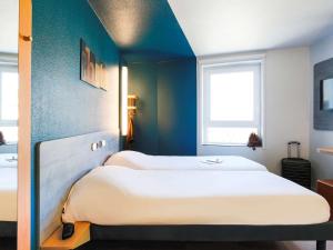 - 2 lits dans une chambre aux murs bleus dans l'établissement ibis budget Bordeaux Centre - Gare Saint Jean, à Bordeaux