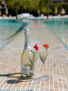 eine Flasche Wein und zwei Gläser neben einem Pool in der Unterkunft The Palm Star Ibiza - Adults Only in Bucht von San Antonio
