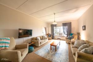 a living room with couches and chairs and a tv at Bella@Jbay in Jeffreys Bay