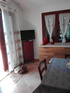 uma sala de estar com uma mesa e uma televisão e uma mesa e cadeira em Villetta relax em SantʼAnna Arresi