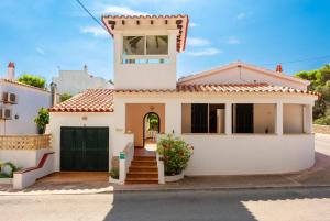 a white house with a green garage at Villa Torreta in Punta Prima
