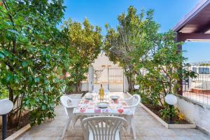 a table and chairs on a patio with trees at Villino Sabrina con piscina in Torre Lapillo