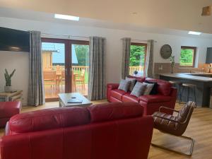 a living room with red couches and a kitchen at Lord Galloway 37 with Hot Tub in Newton Stewart