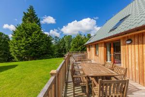 a deck with a table and chairs on a cabin at Lord Galloway 37 with Hot Tub in Newton Stewart