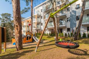 um parque infantil em frente a um edifício com baloiços em Słońce & Plaża Apartamenty Krynica Morska w Nautikka Park em Krynica Morska