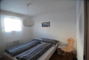 una camera da letto con un letto con lenzuola blu e una sedia di Chesa Brünella, Wohnung Belvair a Zuoz