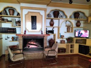 a living room with a fireplace with two chairs and a tv at Casa La Ronda. in Jódar