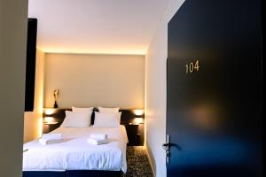 a hotel room with a bed with white sheets at Logis Hôtel & Restaurant Le Vert Bocage in Franqueville-Saint-Pierre