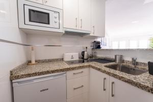 Una cocina blanca con fregadero y microondas. en Apartamento Sunset Algarrobo by Solset, en Algarrobo Costa