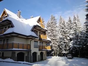 dom pokryty śniegiem i drzewami w obiekcie Apartament Hiszpański w Zakopanem
