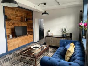 a living room with a blue couch and a tv at The Beulah Apartments in Leeds
