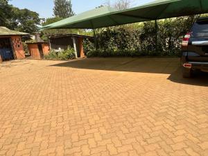 a brick parking lot with a green tent at Rozala Motel in Bondo