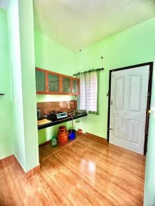a room with a kitchen with green walls and a door at Casita Riverside Villas in Vythiri