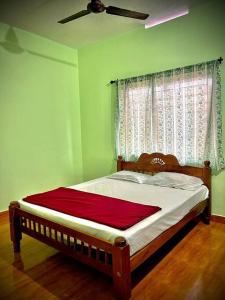 a bed in a green bedroom with a ceiling fan at Casita Riverside Villas in Vythiri