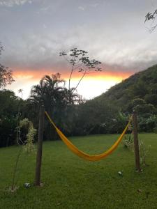 a hammock in a field with a sunset in the background at Pousada Boa Vista in Cachoeiras de Macacu