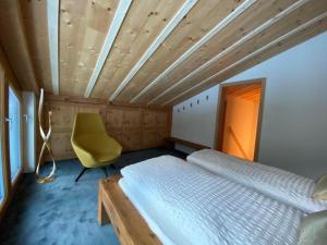 een slaapkamer met een bed en een gele stoel bij Chesa Romana - Dach-Maisonette in Pontresina