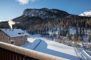 een uitzicht vanaf het balkon van een resort in de sneeuw bij Chesa Romana - Dach-Maisonette in Pontresina