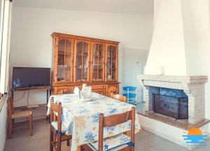 a dining room with a table and a fireplace at Casa Mameli Apartment Villasimius in Villasimius