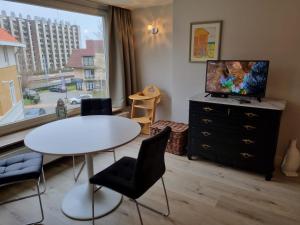 een woonkamer met een tafel en stoelen en een raam bij Residentie Week-end Elisalaan in Nieuwpoort