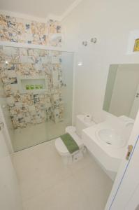 a white bathroom with a toilet and a sink at Pousada Castelo do Rei in Penha