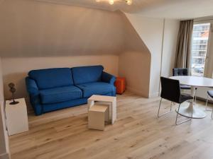 a living room with a blue couch and a table at Residentie Week-end Elisalaan in Nieuwpoort