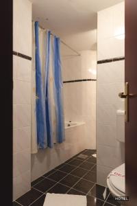 a bathroom with a toilet and a blue shower curtain at MC Hotel in Žalec
