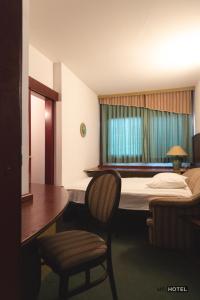 ŽalecにあるMC Hotelのベッド、テーブル、椅子が備わるホテルルームです。