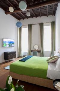 un grande letto verde in una stanza con finestre di Palazzetto de Lante Appartamento Parione a Roma