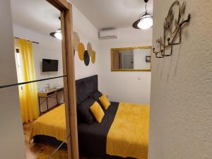 a bedroom with a yellow bed and a mirror at Rooms Argo in Cres