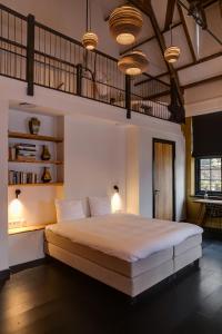 Schlafzimmer mit einem großen Bett mit Beleuchtung und Regalen in der Unterkunft Vesting Hotel Naarden in Naarden