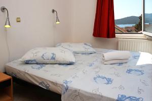 łóżko z niebiesko-białą pościelą i oknem w obiekcie Apartments & Rooms Villa Petra w mieście Žaborić