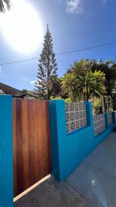 a blue fence with a wooden gate and trees at Pousada das Flores in Fernando de Noronha