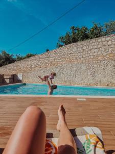 a woman laying on a bed next to a swimming pool at Eucalyptus - The Apartment in Olhos de Água