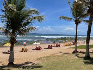 - une plage avec des personnes assises sous des parasols et l'océan dans l'établissement Casa Top Vilas, à Lauro de Freitas