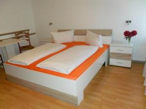 a bedroom with a bed with an orange and white bed frame at Hotel Hirsch in Seebach