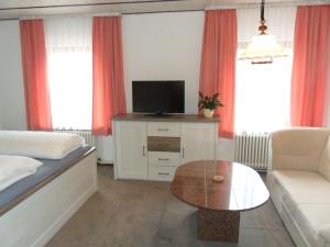 Schlafzimmer mit einem Bett, einem TV und einem Tisch in der Unterkunft Hotel Hirsch in Seebach