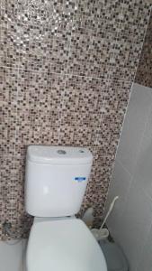 a bathroom with a white toilet in a tiled wall at DAN'S PLACE in Accra
