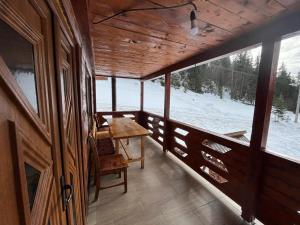 porche de madera con mesa y nieve en el suelo en Cabana Sânziana, en Gârda de Sus