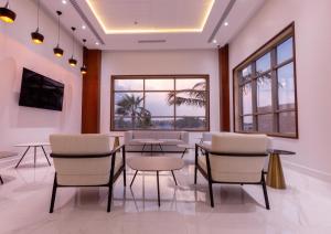 a waiting room with tables and chairs and windows at AlRayah Hotel in Jazan