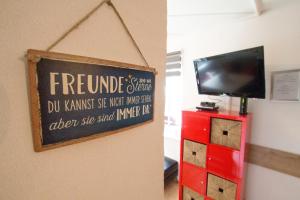 a sign on a wall with a tv and a red dresser at Apartment Peacock - Steinbock Lodges in Zell am See