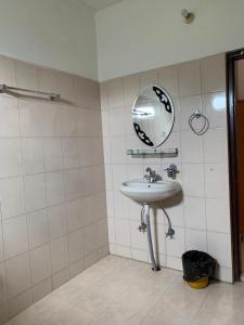 ein Bad mit einem Waschbecken und einem Wandspiegel in der Unterkunft Enchanting Tawang in Tawang