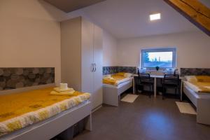 a room with two beds and a desk and a table at Hostel Limaks Celje in Celje