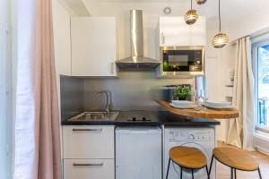 una cucina con lavandino e bancone con sgabelli di Cosy Studio - 2P- Beauregard - 3 a Parigi